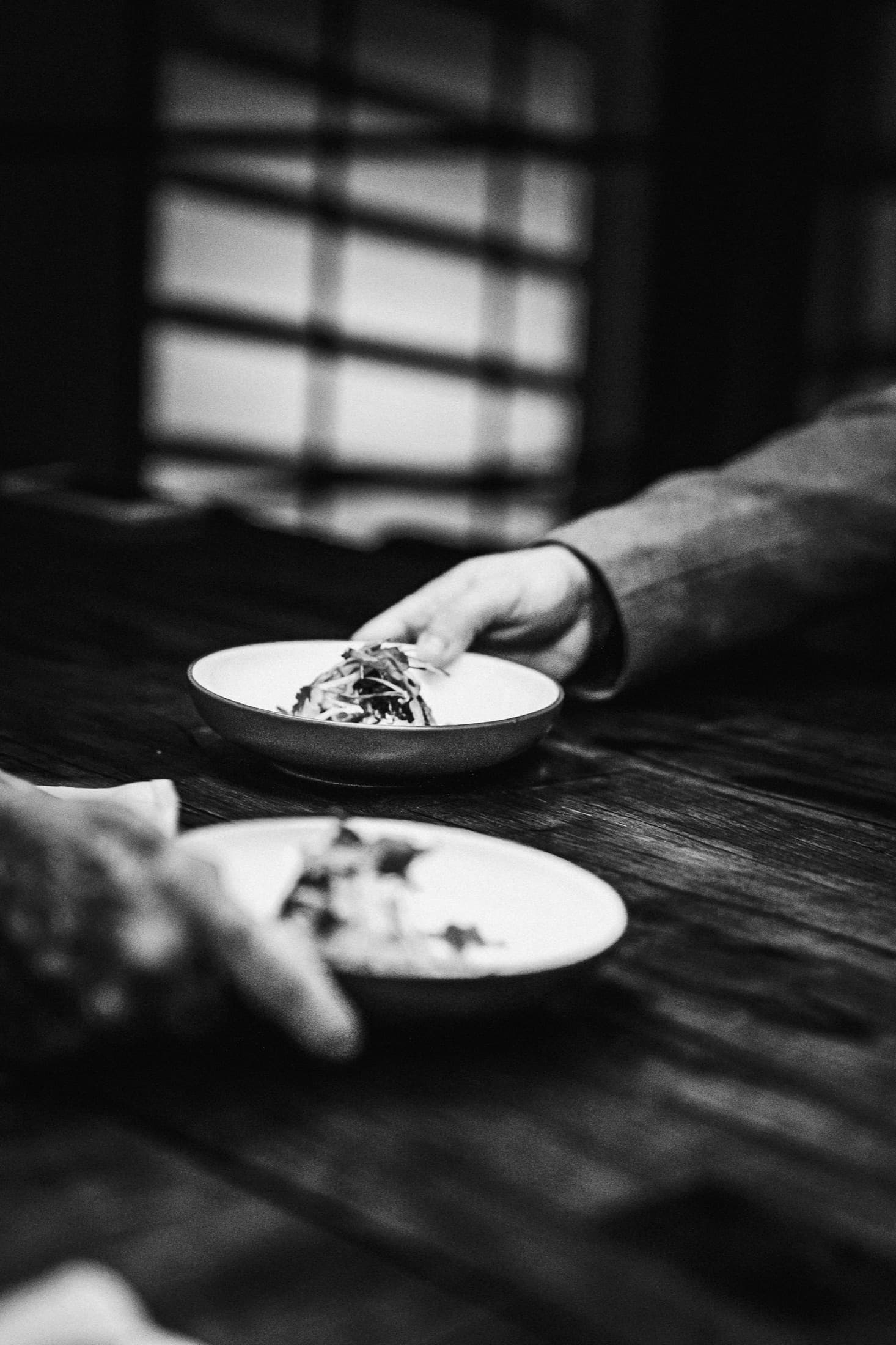 Mains qui se passent un plat sur table en bois brut